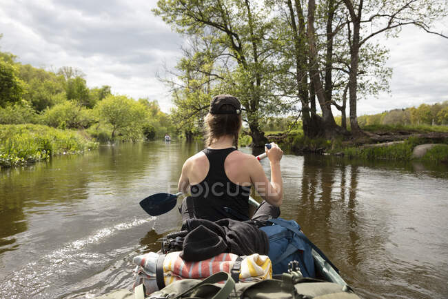 Junge Frau paddelt auf Fluss — Stockfoto