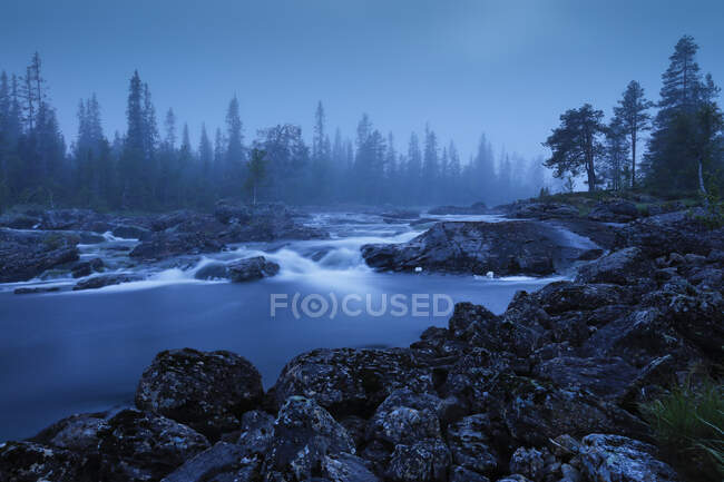 Водопад в реке на закате — стоковое фото