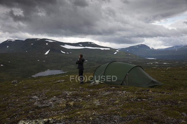 Young woman standing by tent in field — Stockfoto