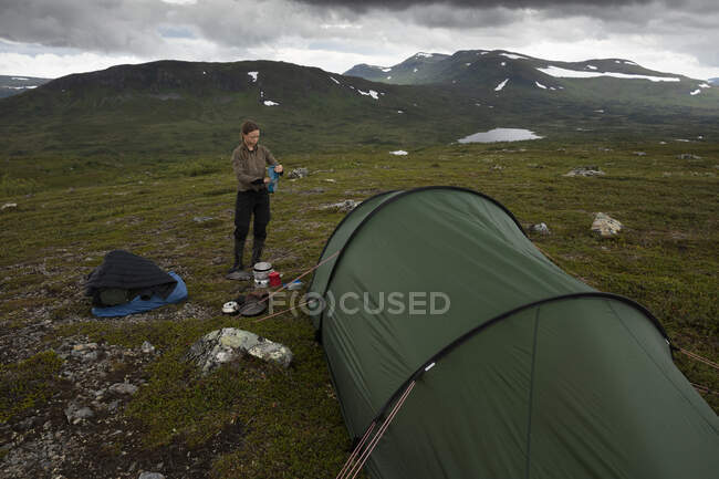 Jeune femme debout près de la tente dans le champ — Photo de stock