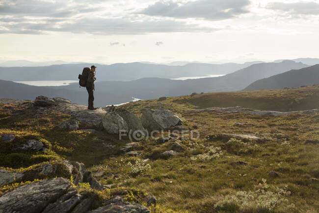 Молода жінка стоїть на скелі біля гір — стокове фото