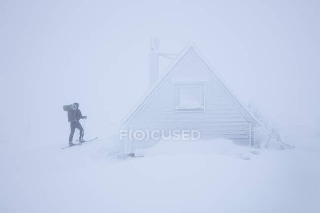 Junge Frau bei verschneiter Hütte — Stockfoto