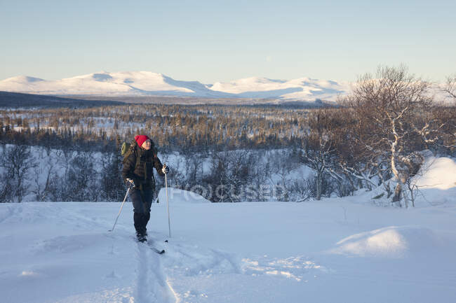 Femme randonnée dans la neige au coucher du soleil — Photo de stock