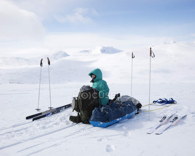 Молодая женщина сидит с сумками в снегу — стоковое фото