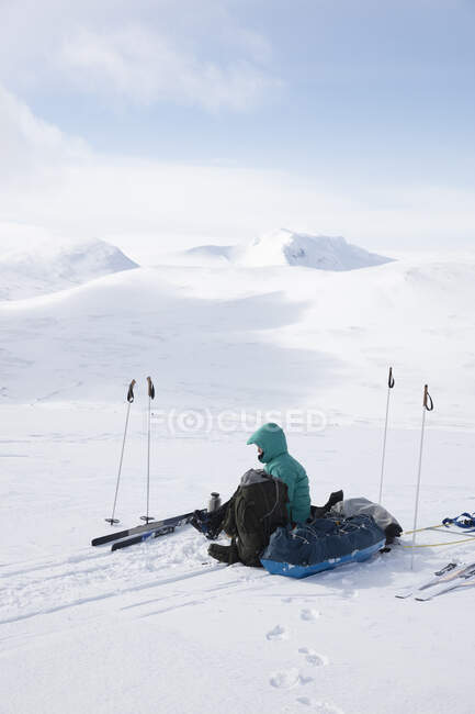 Young woman sitting with bags in snow — Stockfoto