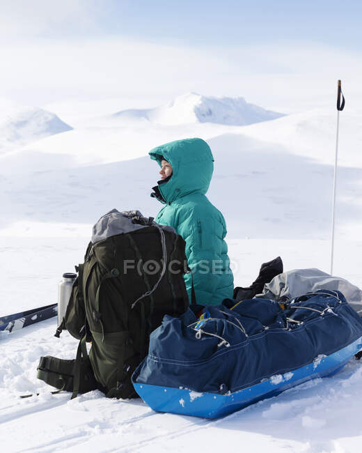 Молода жінка сидить з сумками в снігу — стокове фото