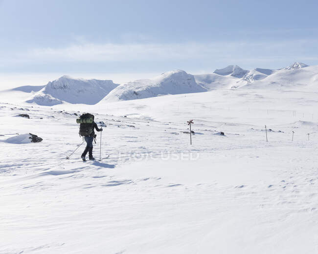 Jovem com postes de caminhada em campo nevado — Fotografia de Stock