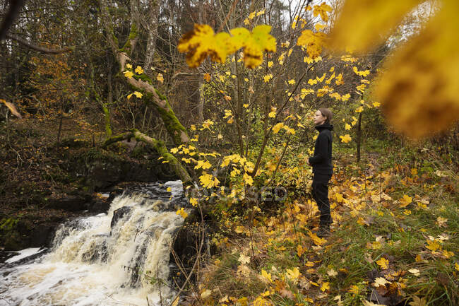 Молодая женщина стоит у водопада — стоковое фото