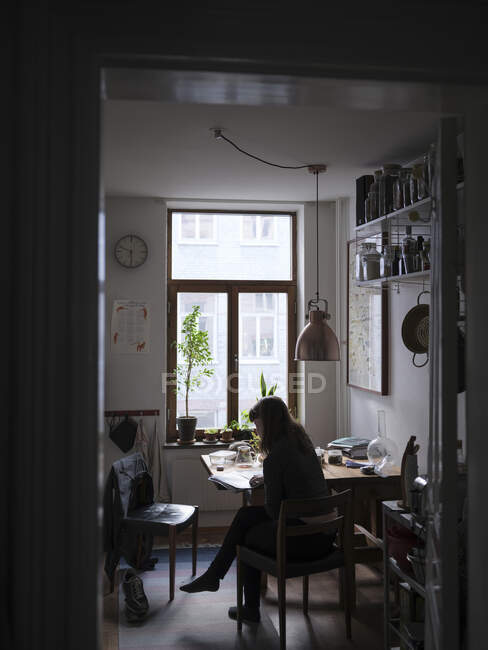 Jovem mulher lendo na mesa de jantar — Fotografia de Stock