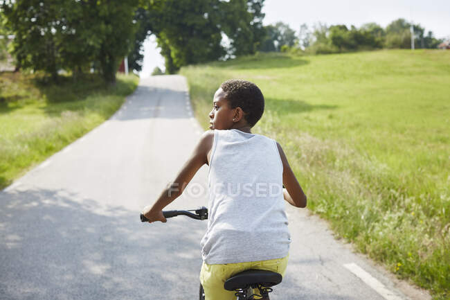 Boy riding bicycle on road — Fotografia de Stock