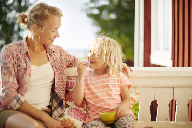 Smiling mother and daughter sitting on balcony — Stock Photo