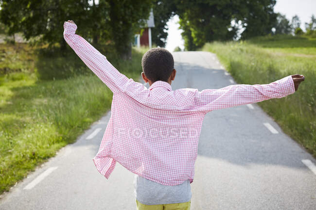 Boy in pink shirt walking on road — Photo de stock
