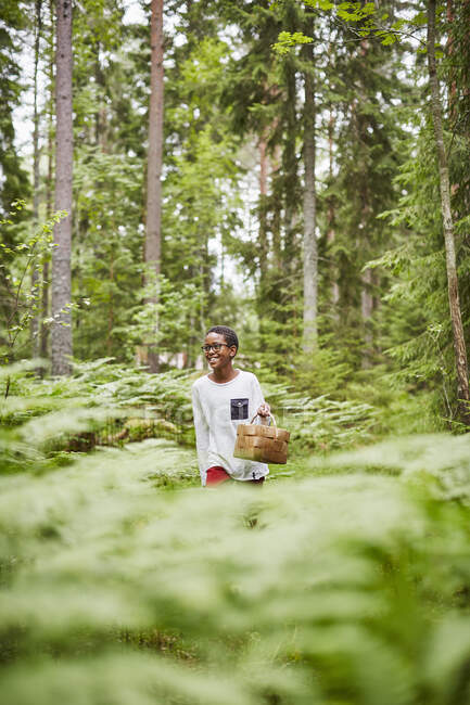 Мальчик с корзиной в лесу — стоковое фото