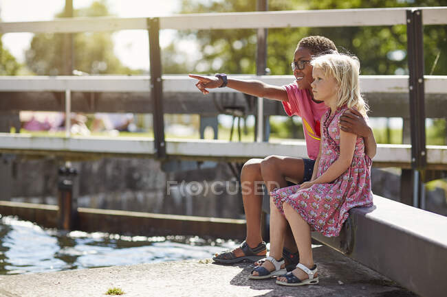 Siblings sitting by canal — Stockfoto