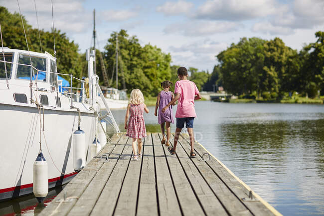 Geschwister spazieren mit Boot auf Steg — Stockfoto