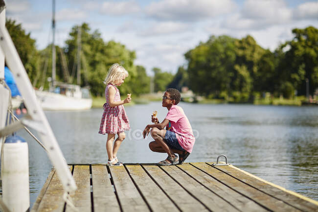 Siblings with ice cream cones on jetty — Stock Photo