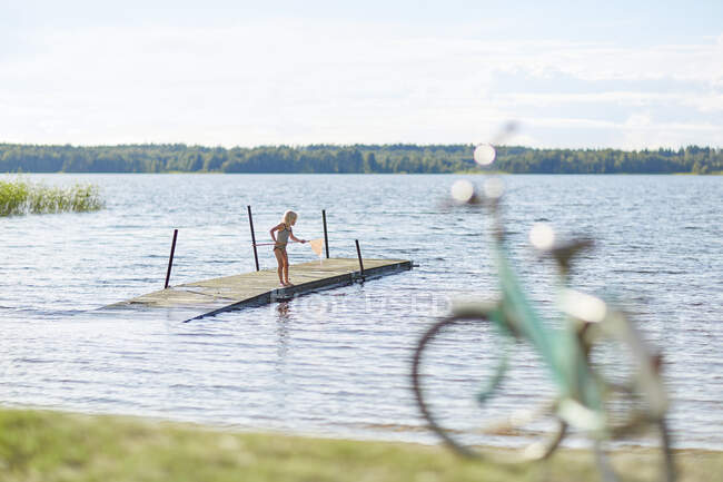 Chica jugando con la red en embarcadero en el lago Skargen, Suecia - foto de stock