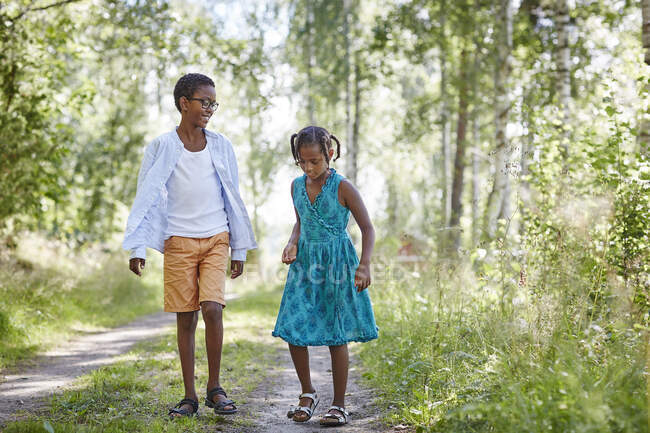 Hermanos caminando en el camino en el bosque - foto de stock