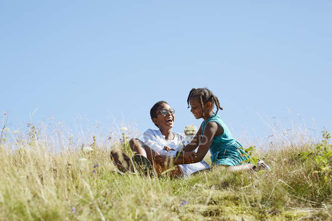 Smiling siblings sitting on hill — Stock Photo