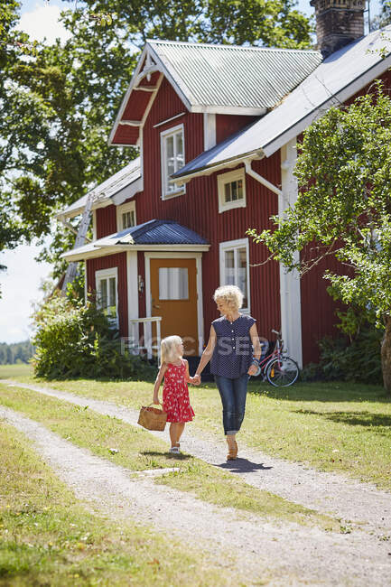 Mother and daughter walking with basket on driveway — Stockfoto