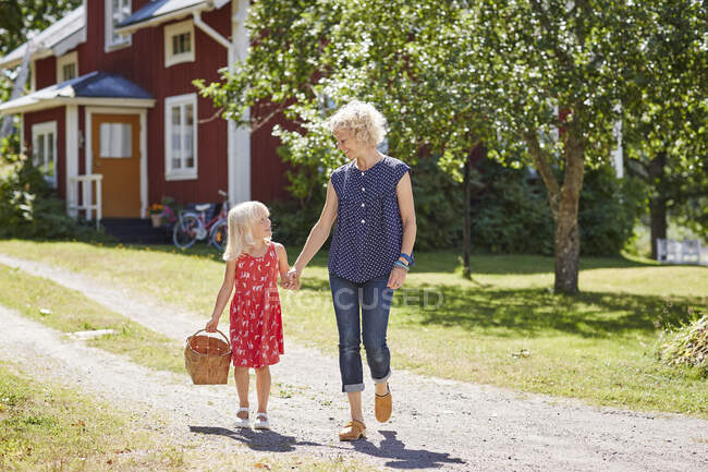 Mother and daughter walking with basket on driveway — Stock Photo