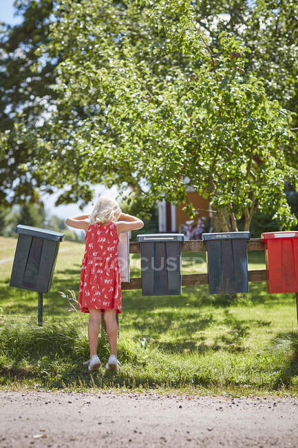 Mädchen im roten Kleid checkt Briefkasten — Stockfoto
