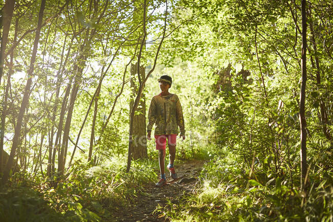 Boy walking on path in forest — Stockfoto