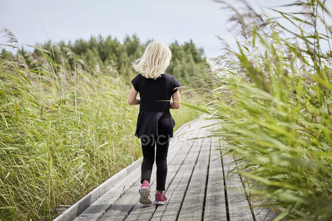 Girl walking on boardwalk — Stockfoto