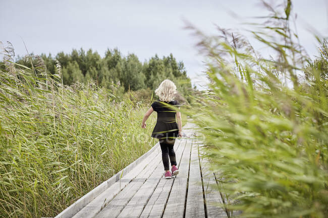 Girl walking on boardwalk - foto de stock