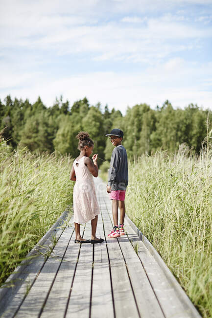 Siblings walking on boardwalk — Stockfoto