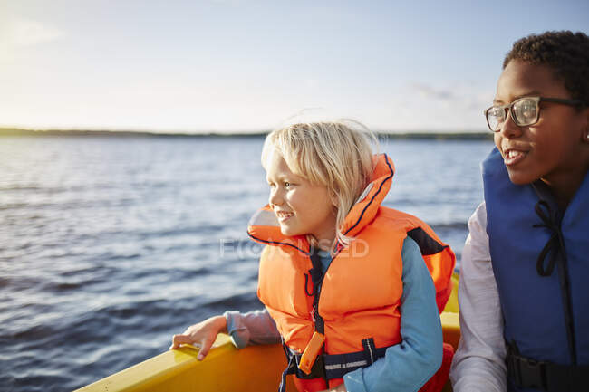 Siblings sitting in boat on lake — Stockfoto