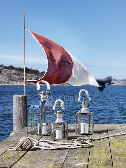 Bandeira e lanternas no molhe pelo mar — Fotografia de Stock