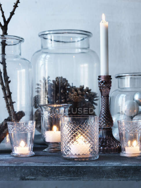 Bougies et cônes de pin dans des pots en verre — Photo de stock