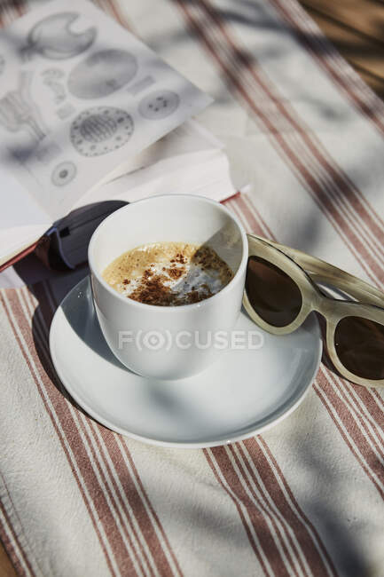 Cappuccino, óculos de sol e livro — Fotografia de Stock