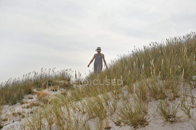 Женщина в полосатом платье на песчаных дюнах — стоковое фото
