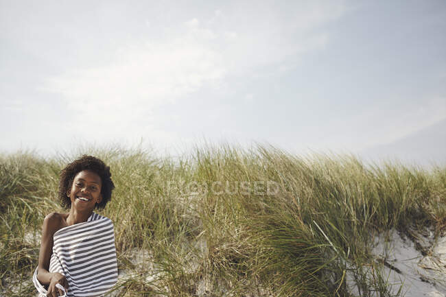 Garoto sorridente em toalha listrada em dunas — Fotografia de Stock