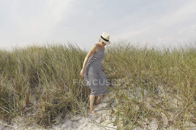 Женщина в полосатом платье на песчаных дюнах — стоковое фото