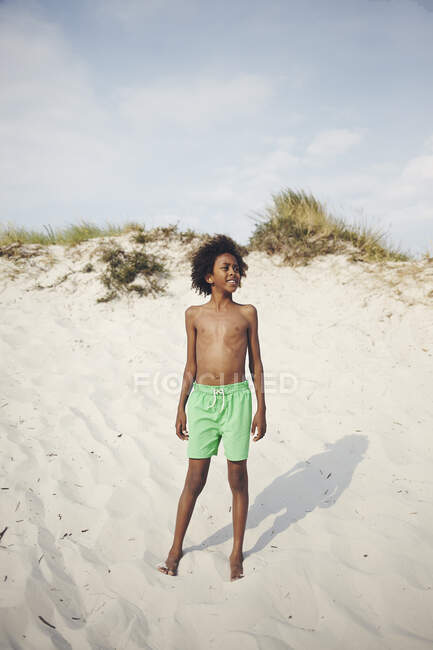 Boy in swim trunks on sand dune — Photo de stock
