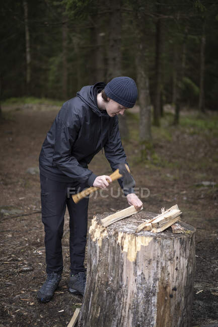 Хлопчик-підліток подрібнює дрова на дереві пень — стокове фото