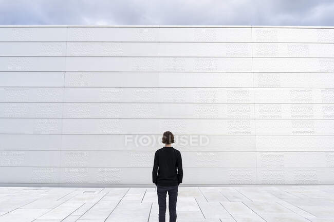 Vista posteriore del ragazzo adolescente da parete bianca — Foto stock