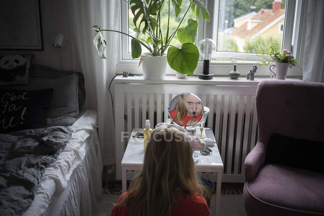 Teenage girl applying make-up in mirror — Foto stock