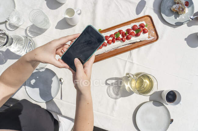 Mãos de menina adolescente tirando foto de sobremesa de morango — Fotografia de Stock