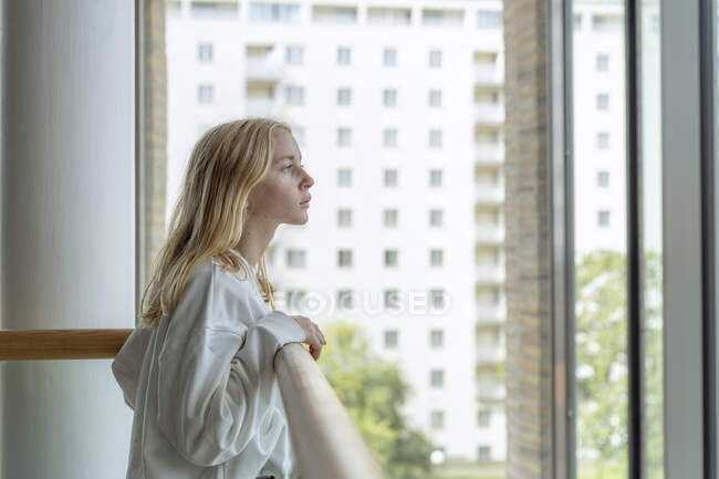 Девочка-подросток на перилах смотрит в окно — стоковое фото