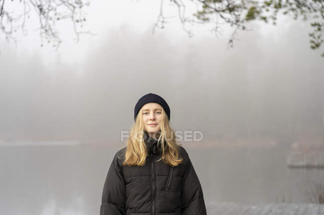 Adolescente chica por lago en la niebla - foto de stock