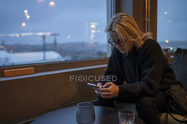 Woman using smart phone window — Stockfoto