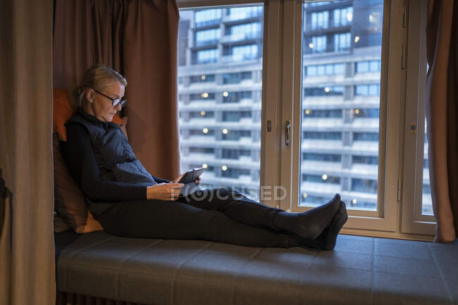 Женщина с помощью планшета за окном — стоковое фото