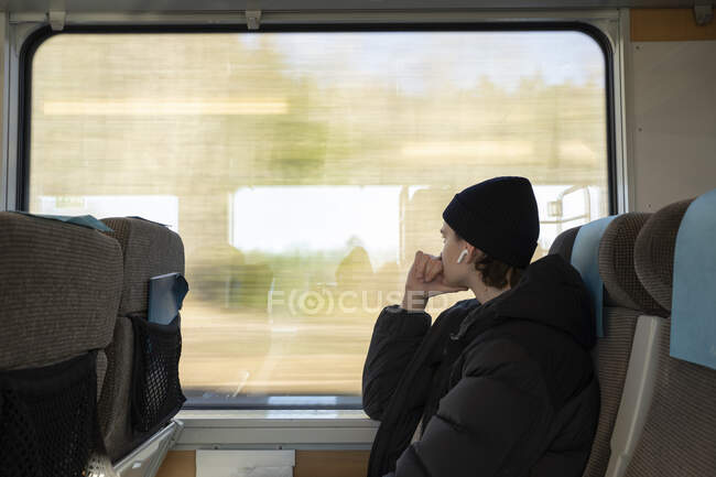 Young man sitting at window on train — Foto stock