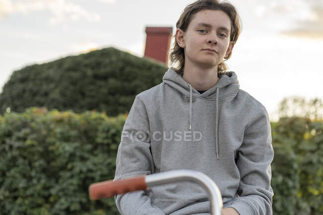 Молодой человек в капюшоне сидит на велосипеде — стоковое фото