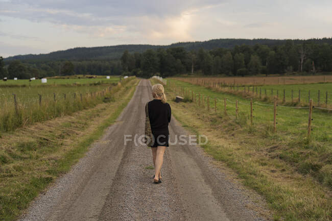 Mulher caminhando na estrada rural — Fotografia de Stock