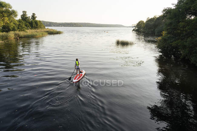 Jovem paddleboarding no lago — Fotografia de Stock
